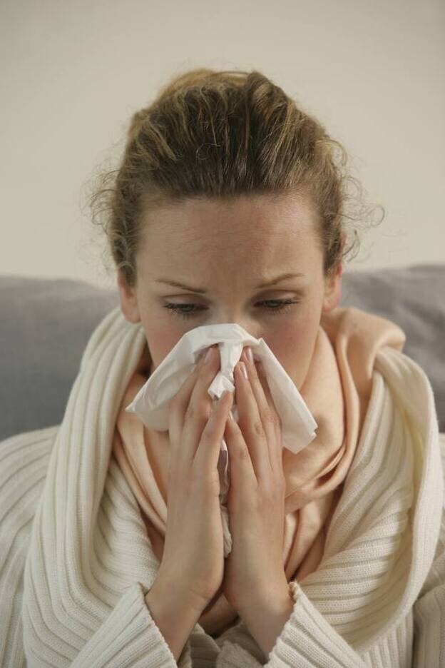Una mujer resfriada se limpia la nariz con un pañuelo./GTRES