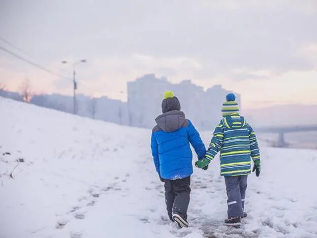 Dos niños paseando por un paisaje nevado./getty