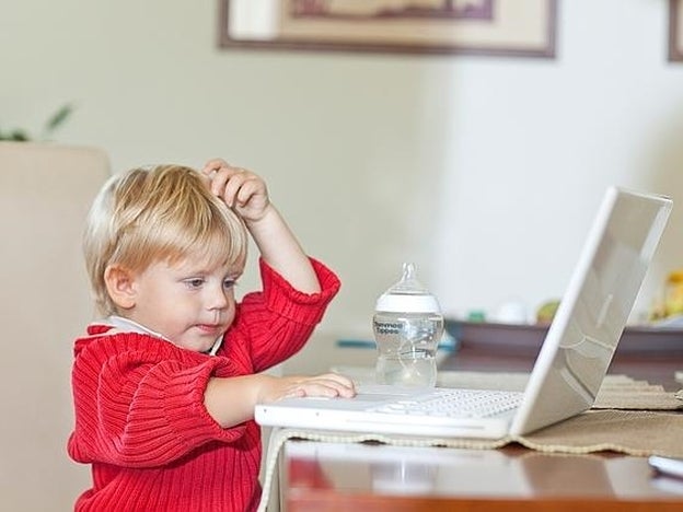 Un niño sorprende a su padre consultando el ordenador./GTRES