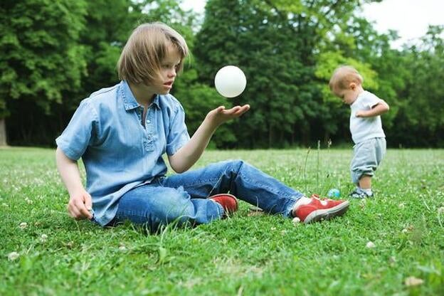 Una niña con síndrome de Down, jugando en el parque./GTRES