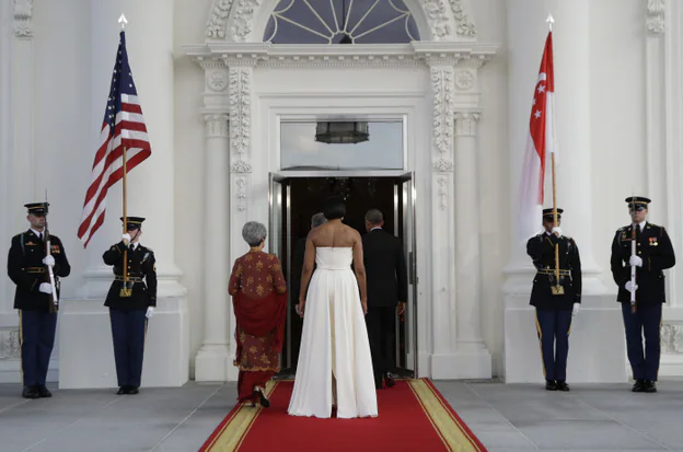 Detalle de la espalda con cola del vestido de Michelle Obama, y su diferencia de talla con la Primera Dama de Singapur.
