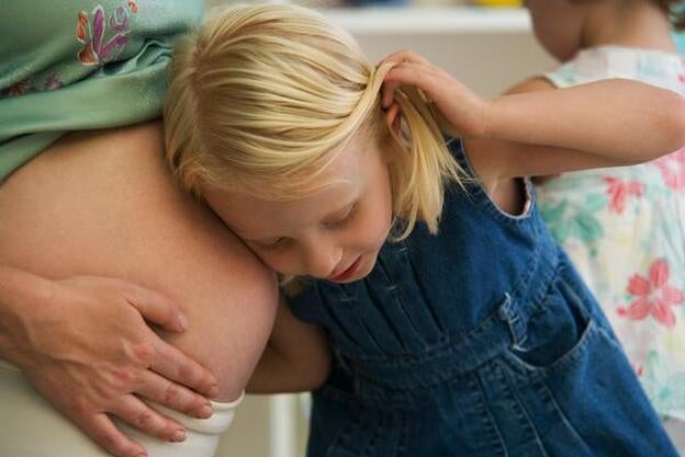 Una niña apoyada en la barriga de su mamá./GTRES