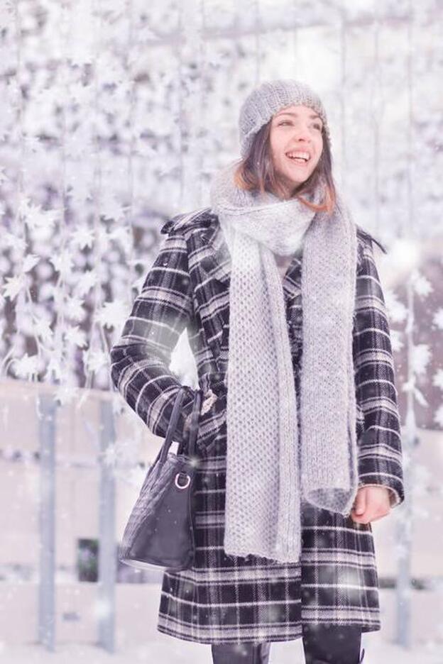 Una mujer sonriente mientras nieva/fotolia