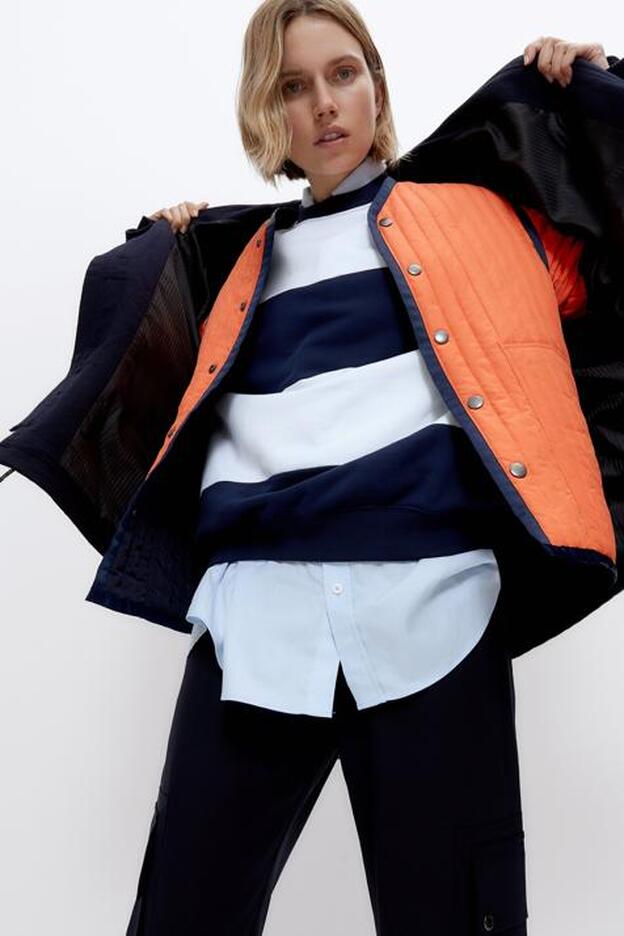 En azul marino con detalles en naranja, este chaquetón reversible es desmontable y te dará mucho juego.