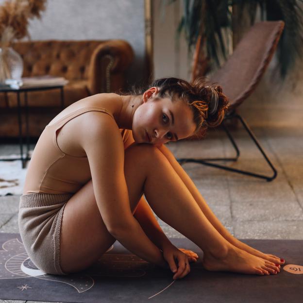 Mujer sentada descansando después de hacer deporte, con la cabeza apoyada sobre las rodillas. 