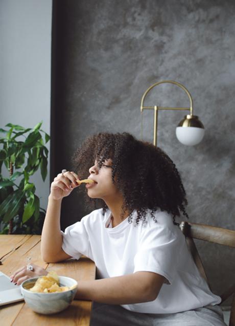 Mujer comiendo patatas/PEXELS