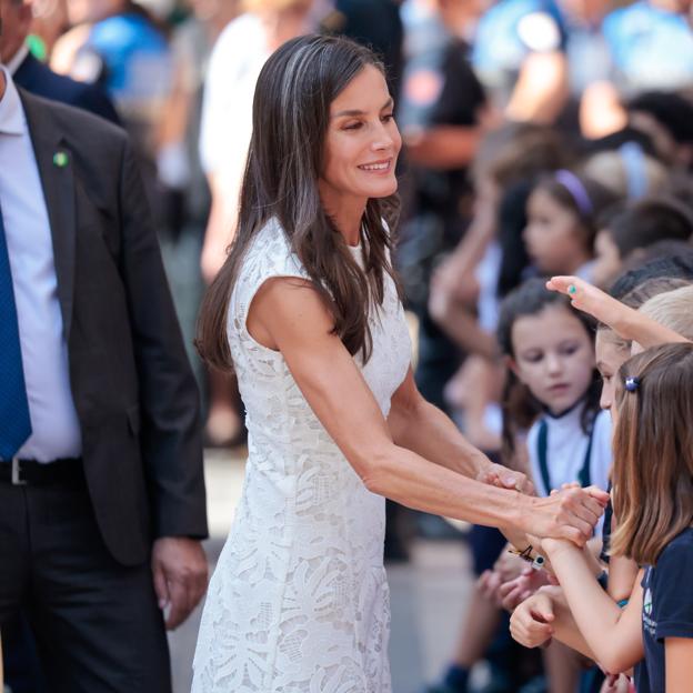 La reina Letizia con vestido blanco saludando a la gente. 