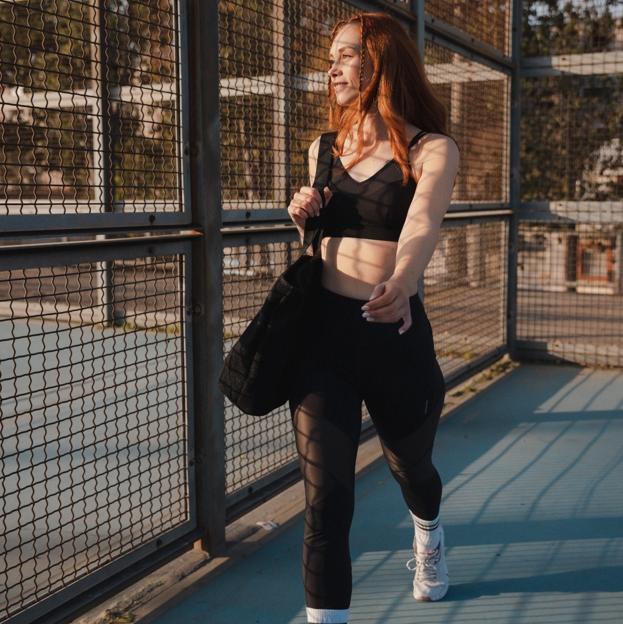 Mujer joven con ropa deportiva acudiendo a una pista para hacer deporte. 