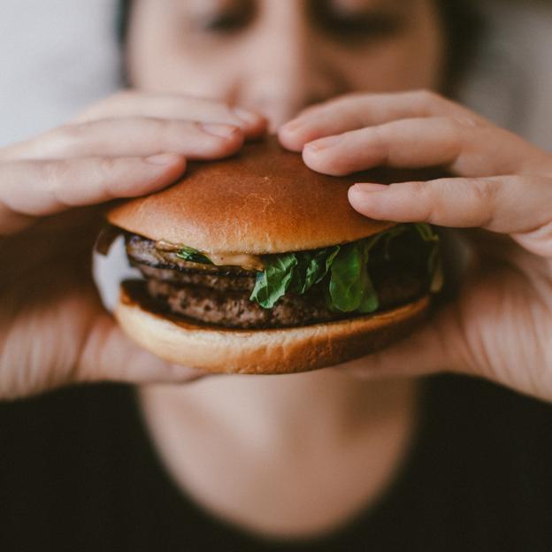 Mujer comiendo una hamburguesa. 