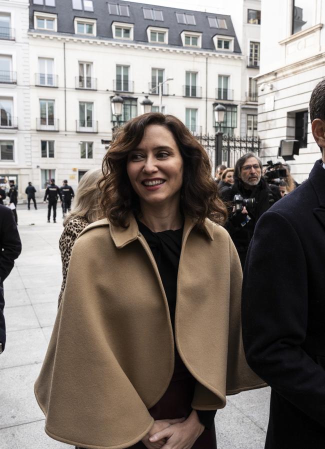 Isabel Díaz Ayuso con capa cortita y falda efecto piel burdeos.