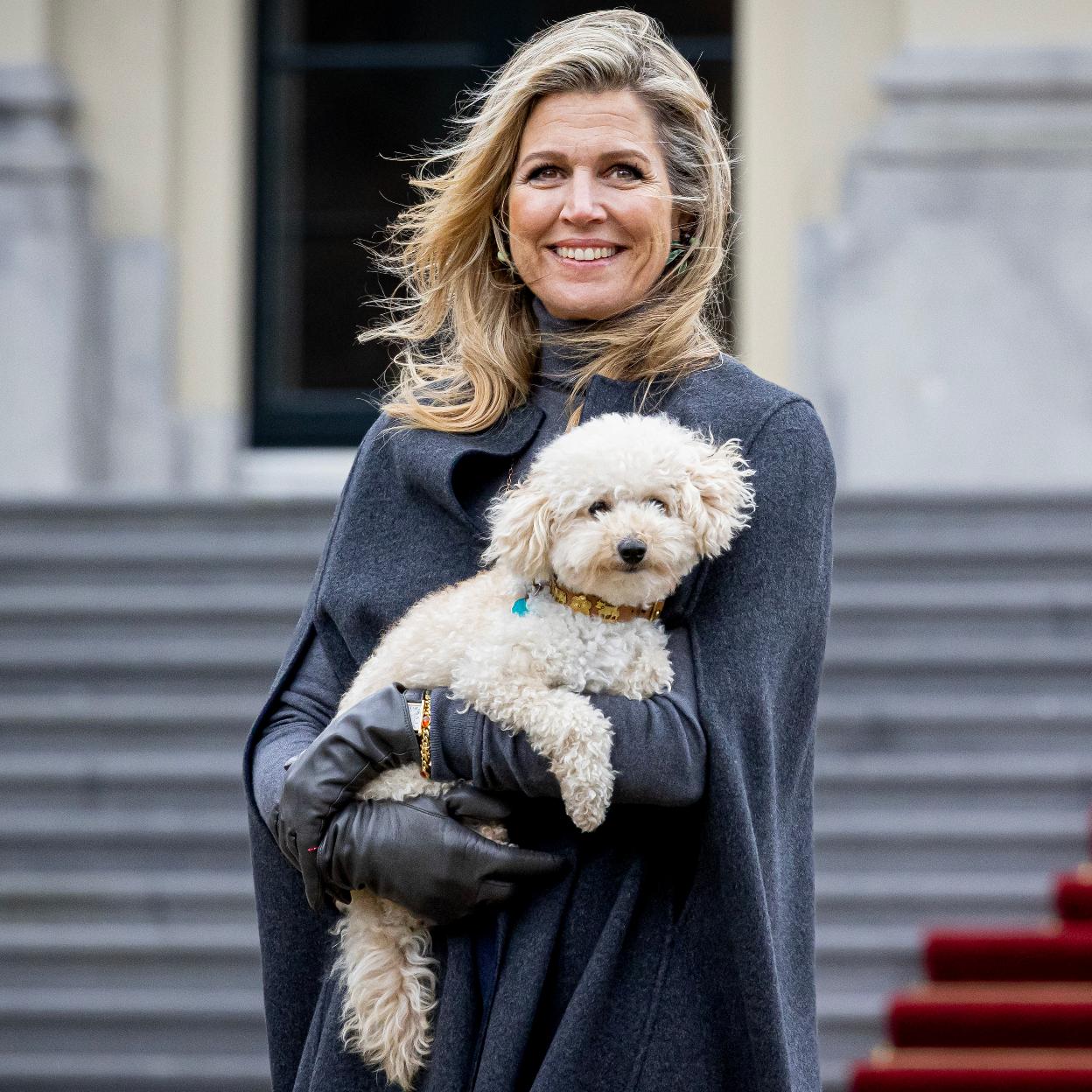 Máxima de Holanda, de gris, posa con su mascota. /GETTY IMAGES