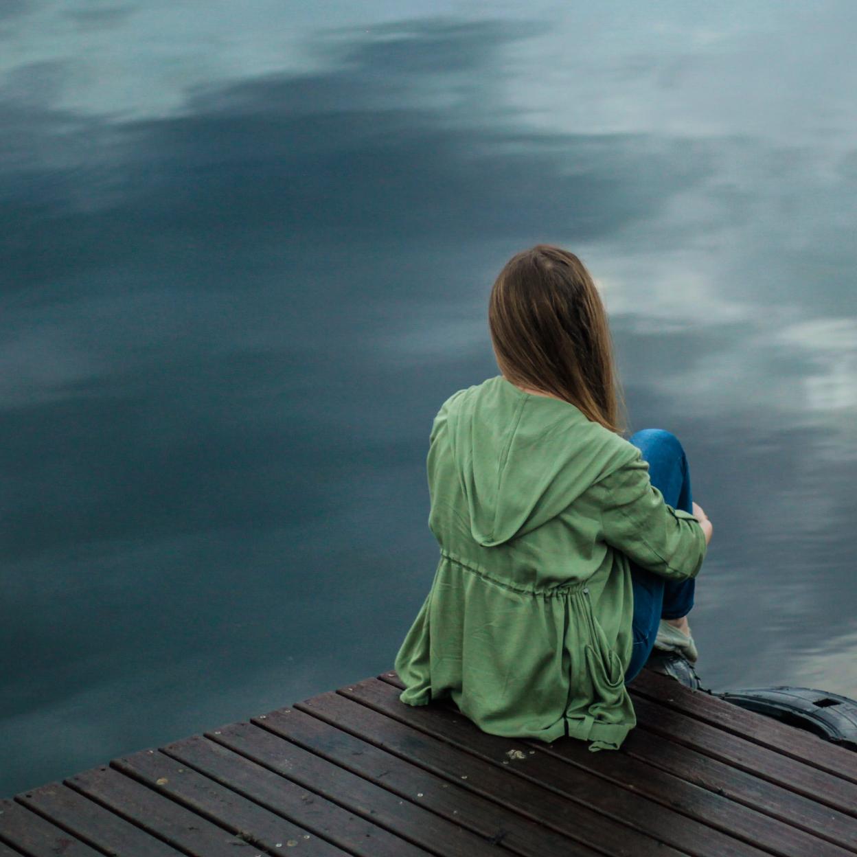 Mujer sentada en un muelle mirando al mar. /Foto de Keenan Constance en Pexels.