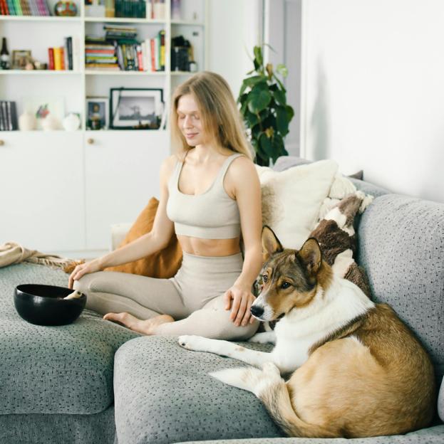 Mujer meditando en casa con su mascota. /