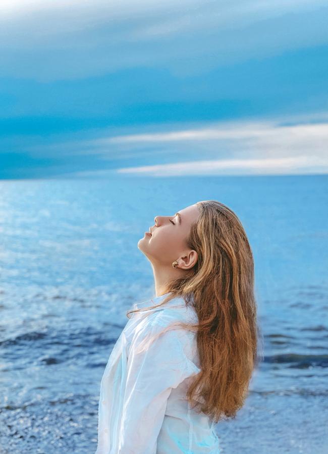 Mujer meditando frente al mar. / PEXELS