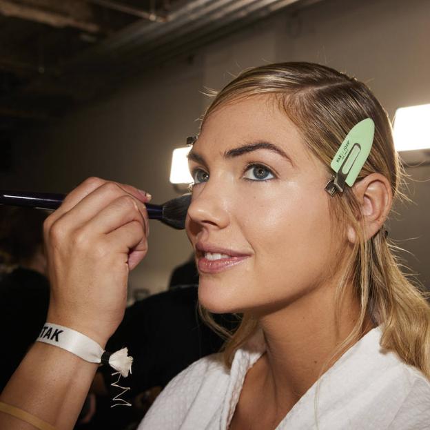 Maquillador usando brocha para iluminador en modelo