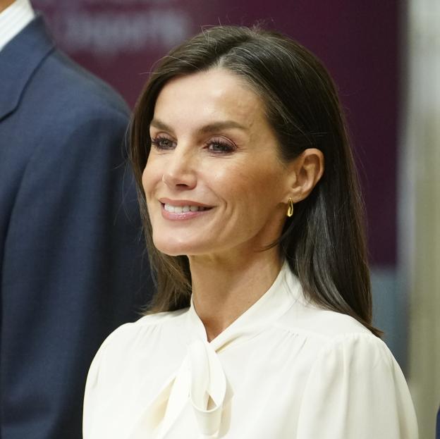 La reina Letizia con una blusa blanca con lazada al cuello.