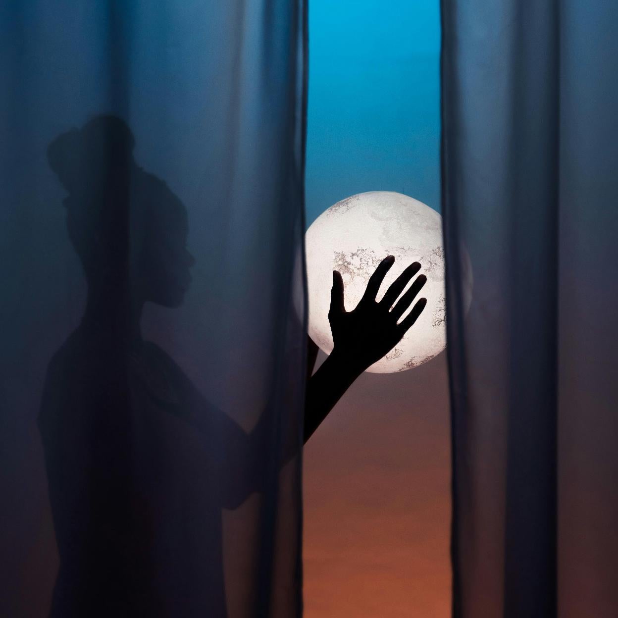 Mujer sujetando una luna llena. /pexels