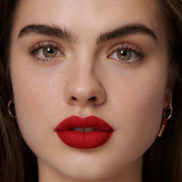 Modelo con maquillaje tendencia minimal de labios rojos y máscara de pestañas